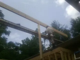 Carpenter setting a ridge beam over a new addition frame — Ice Dam Removal by Roofing Brothers in Daleville